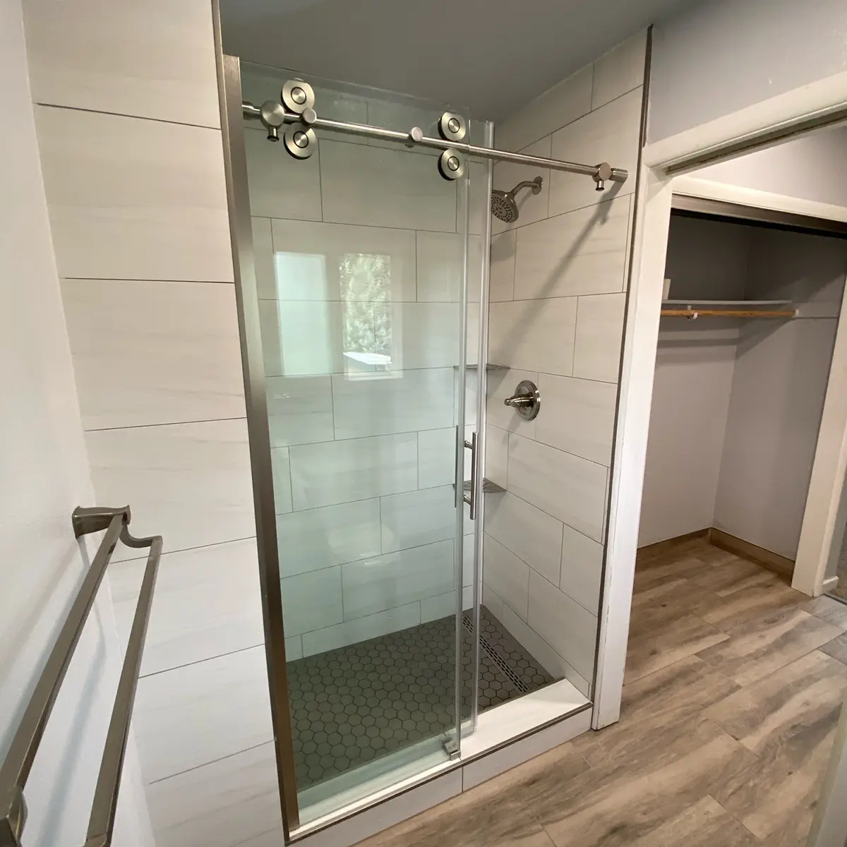 A beautiful glass shower with tile surround in a bathroom with LVP flooring