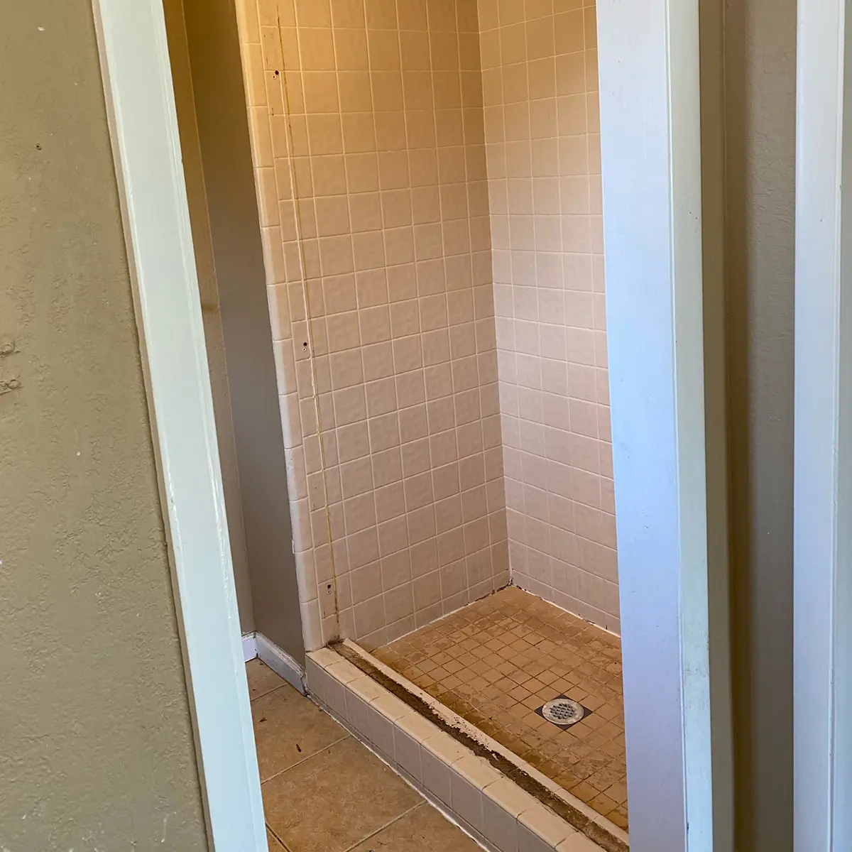 A bathroom remodel with a dated tiled shower being replaced