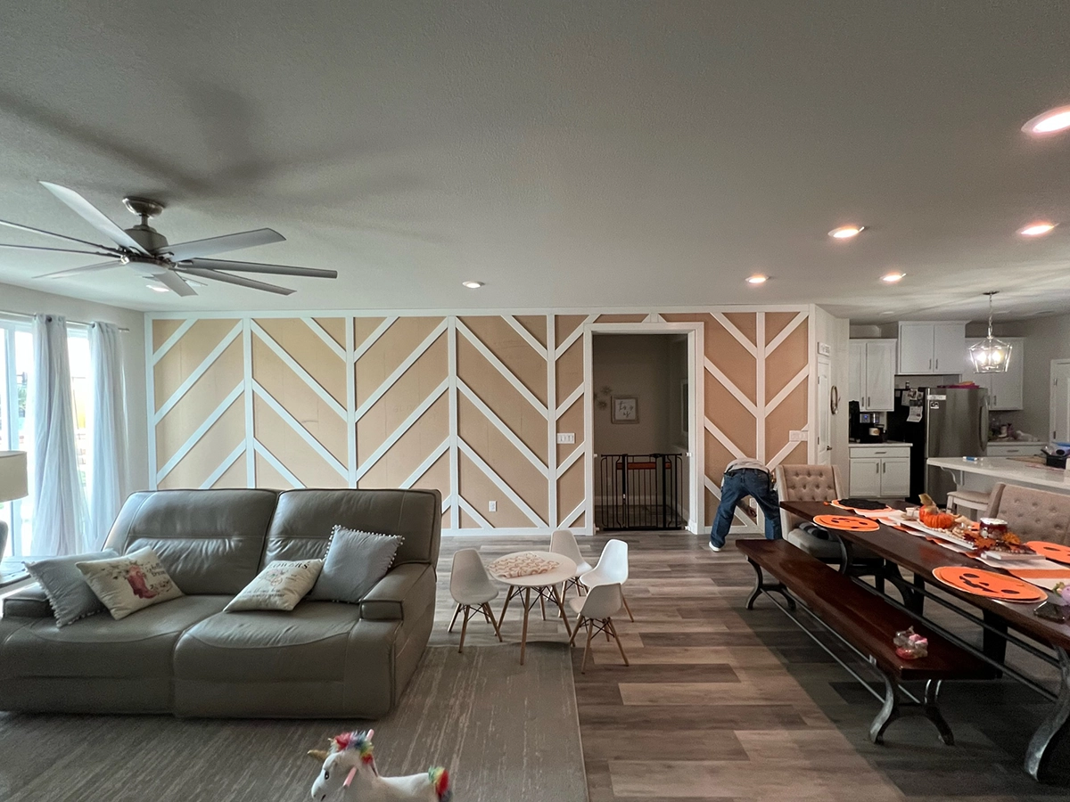 A living space with luxury vinyl plank flooring, a gray couch, a table, and an open space kitchen