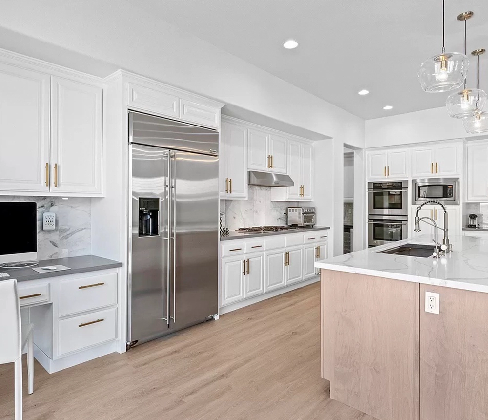 Kitchen cabinets with golden hardware and a large island with pendant lights