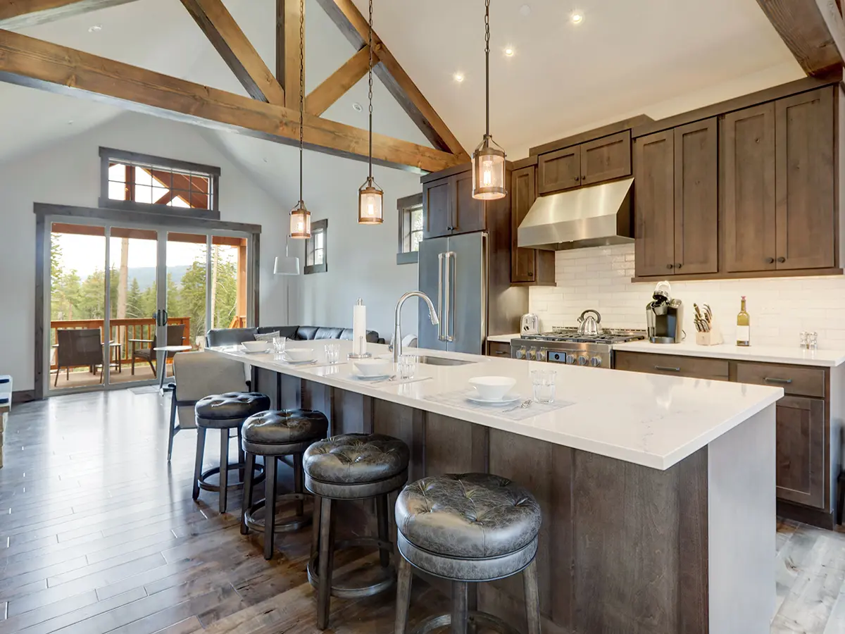 A large rectangular kitchen island with a slab quartz countertop, wood cabinets, and wood flooring