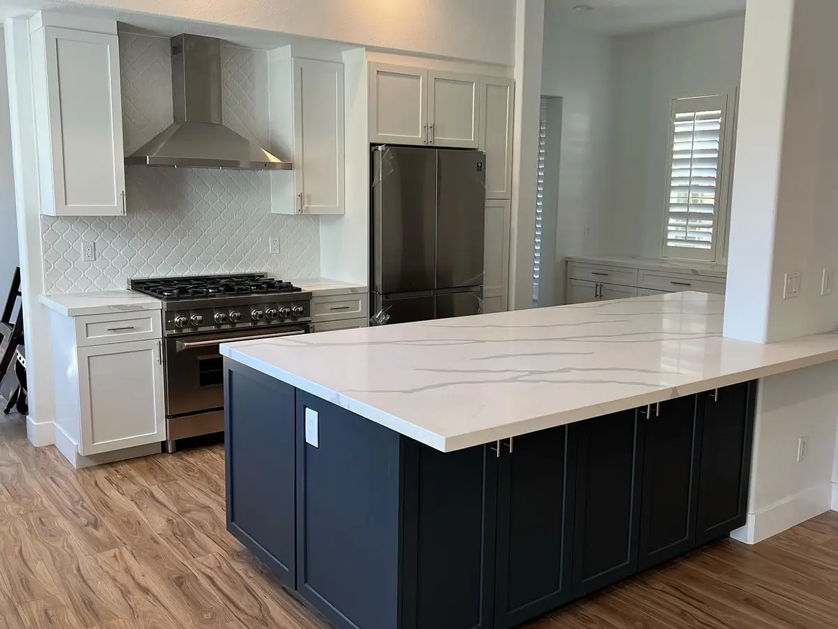 A large kitchen island with a quartz countertop and white cabinets
