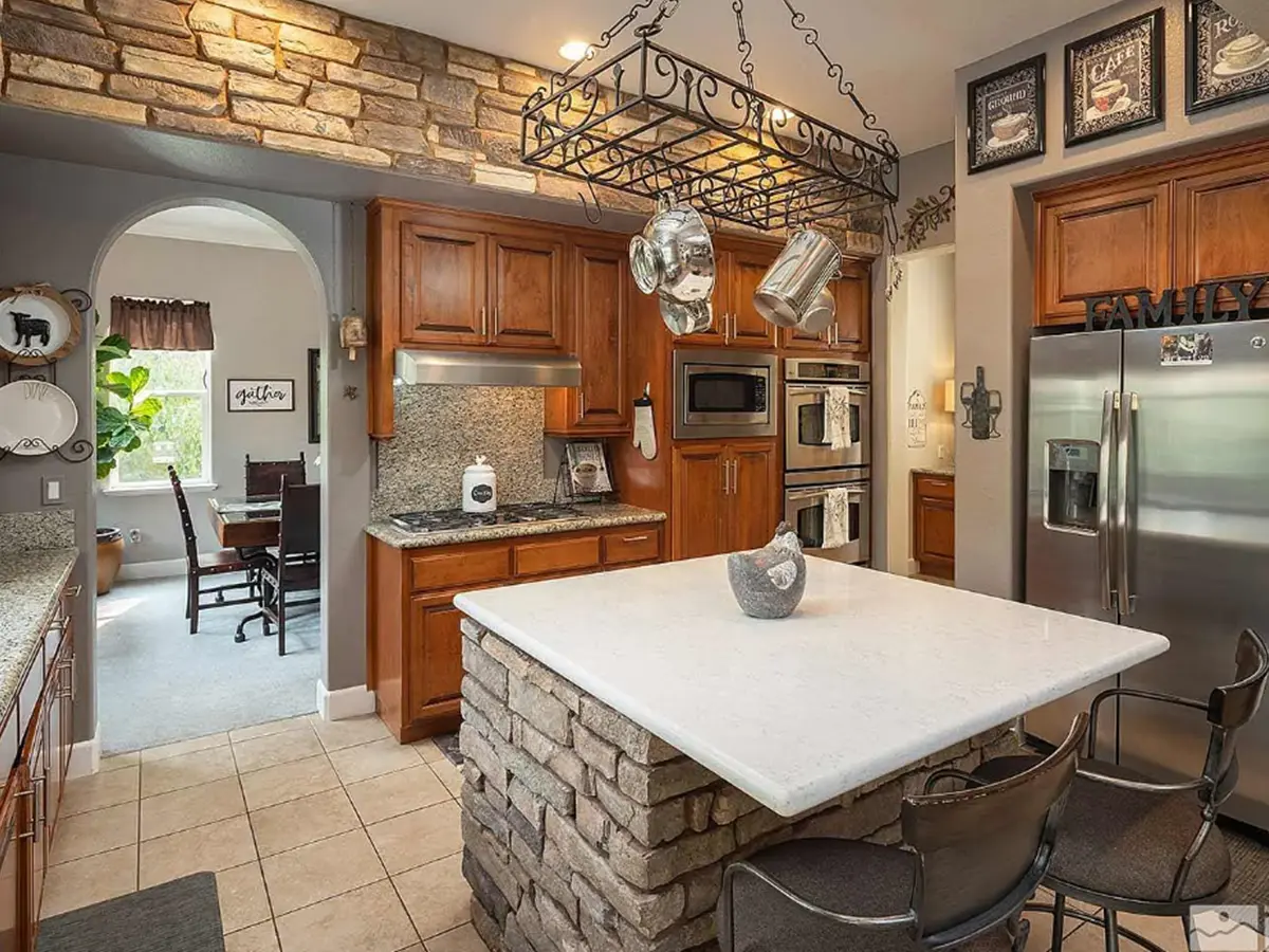 A small, stone kitchen island with a small quartz countertop and dated kitchen cabinets
