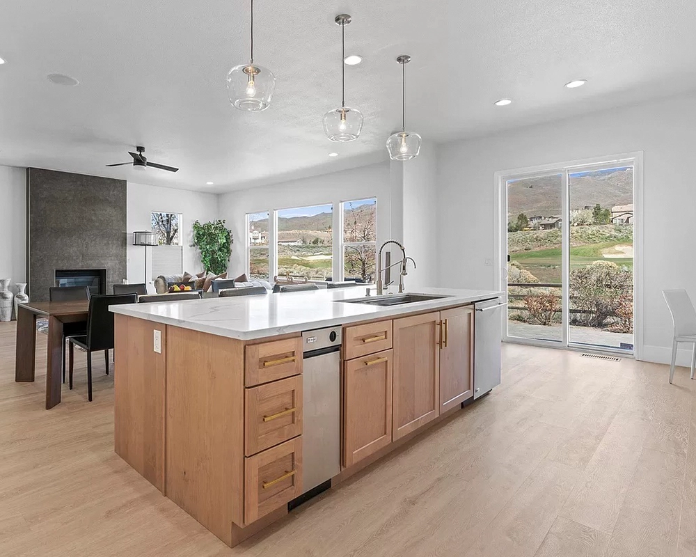 Large kitchen island with wood cabinets and pendant lights