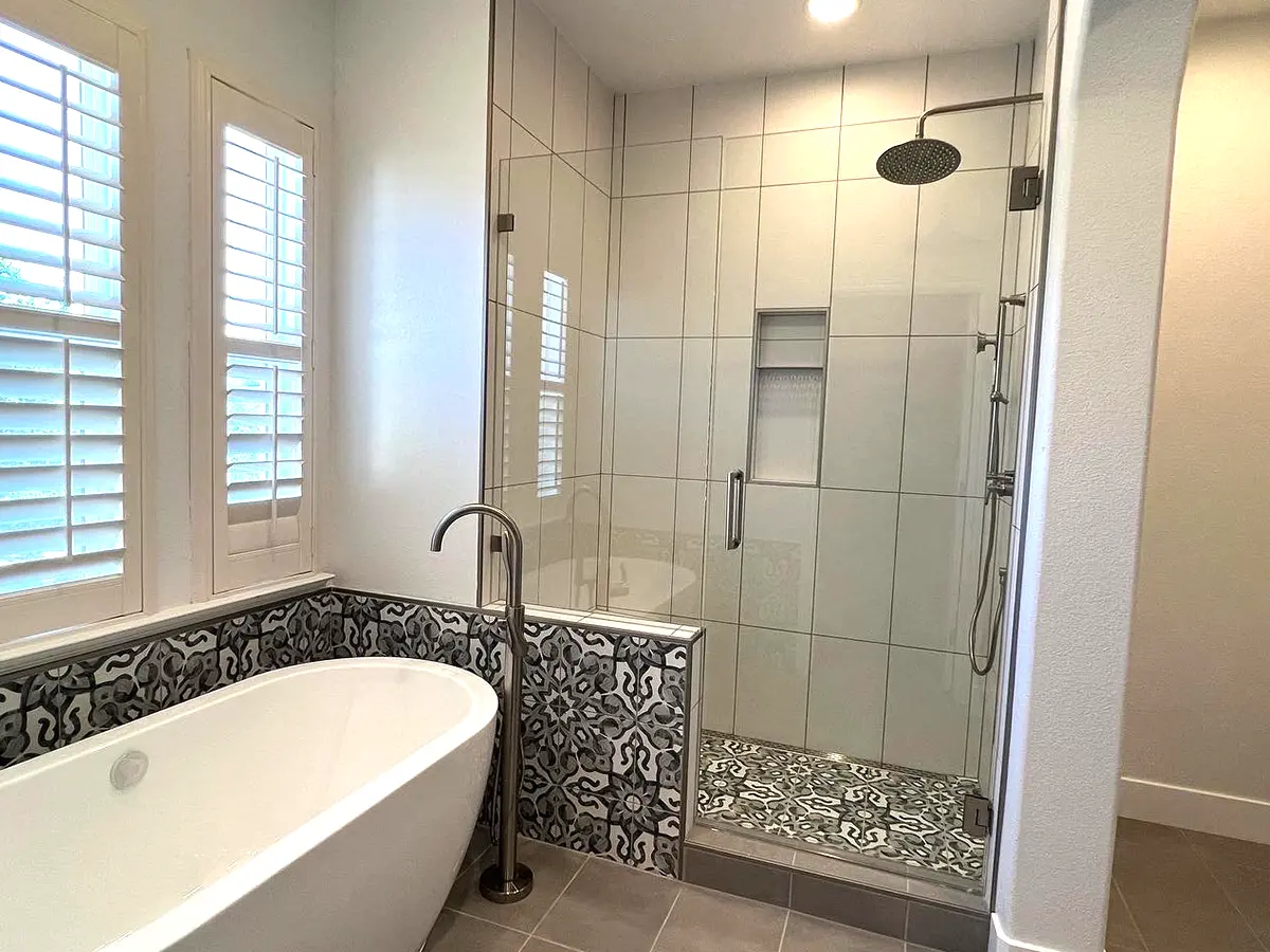A freestanding tub with a glass shower with beautiful tile design