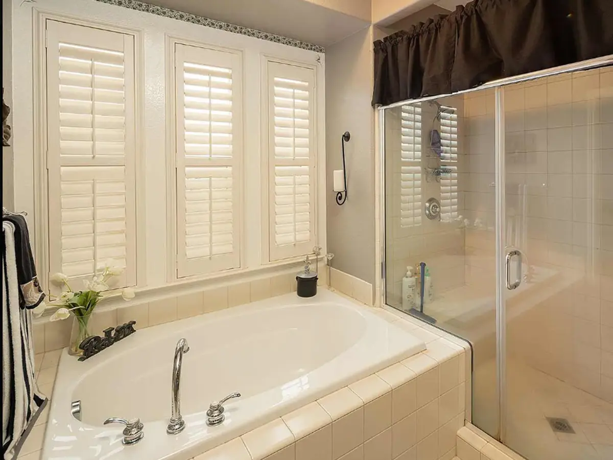 A large tub with a shower with glass panels