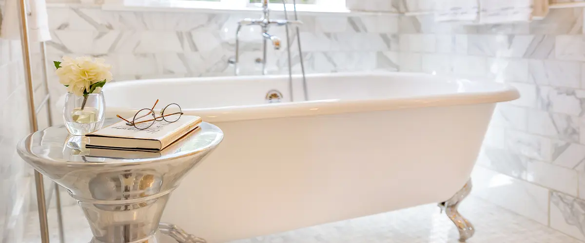 A freestanding bathtub with a small, fancy table