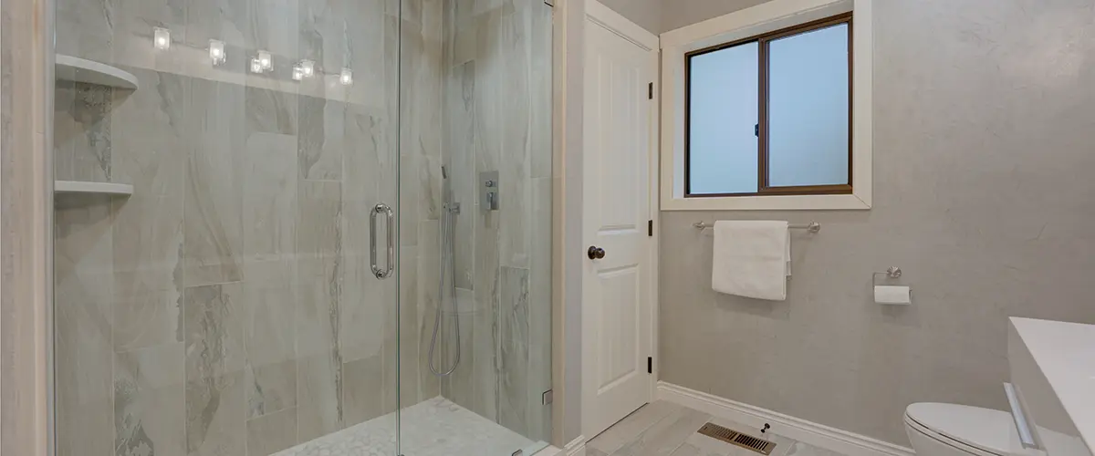 A glass walk-in shower in a bath with tile flooring