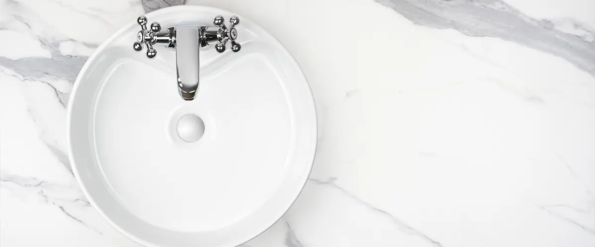 A white bowl sink with a quartz countertop
