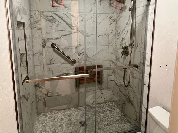 A shower with glass door and tiled walls