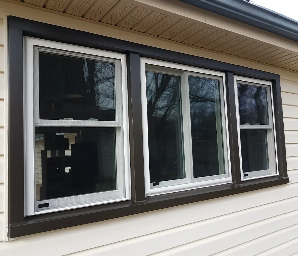 Window replacement with dark frame and white vinyl siding on home