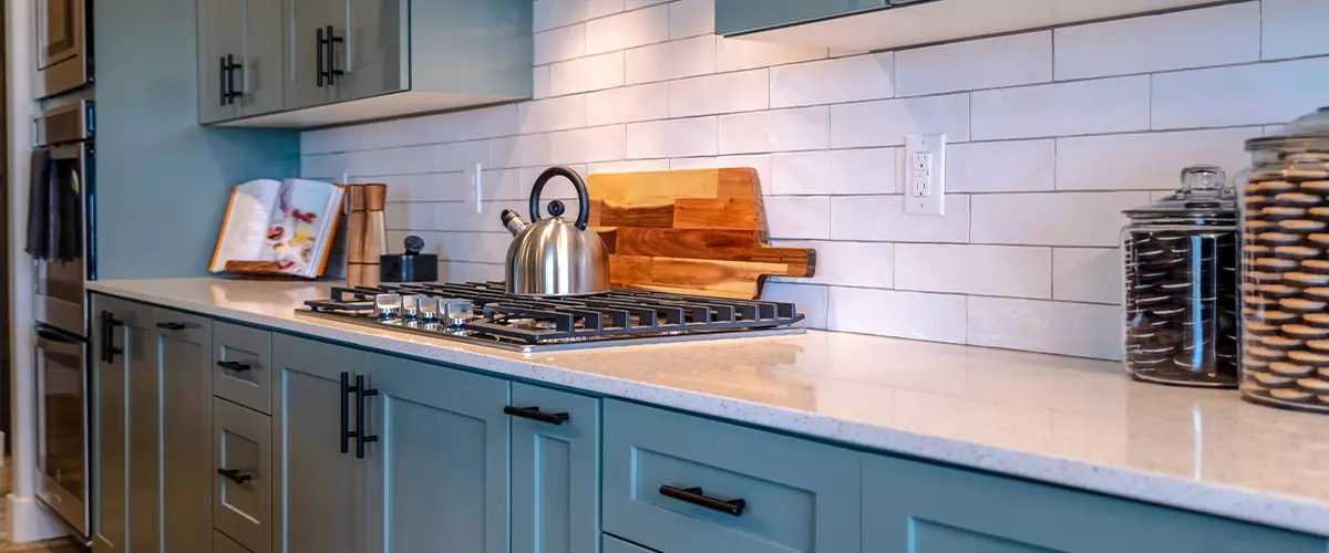 Cooking Area Of Home With Cabinets And Exhaust Hood Over Cooktop And Countertop.webp