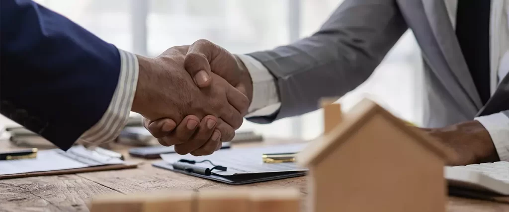 Hiring a general contractor, sales representative shakes hands with a customer and offers a home purchase contract