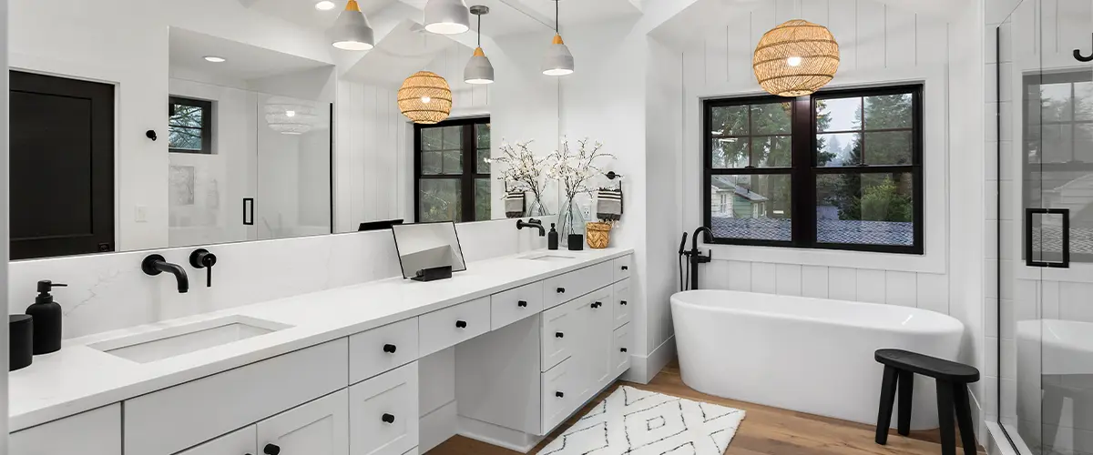 Modern bathroom remodeling in Saddlehorn. with double vanity, white cabinetry, black fixtures, freestanding bathtub, and glass-enclosed shower under vaulted ceilings