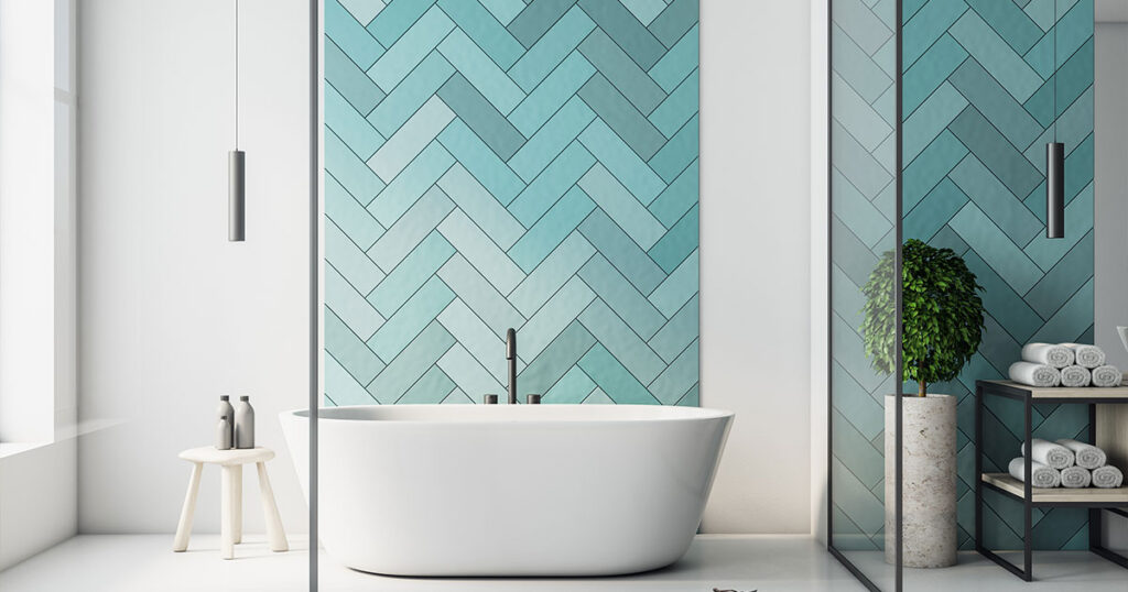 Modern bathroom with freestanding tub, teal herringbone tiles, minimalist decor, and natural light showcasing types of bathroom tiles.