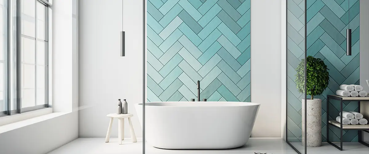 Modern bathroom with freestanding tub, teal herringbone tiles, minimalist decor, and natural light showcasing types of bathroom tiles.