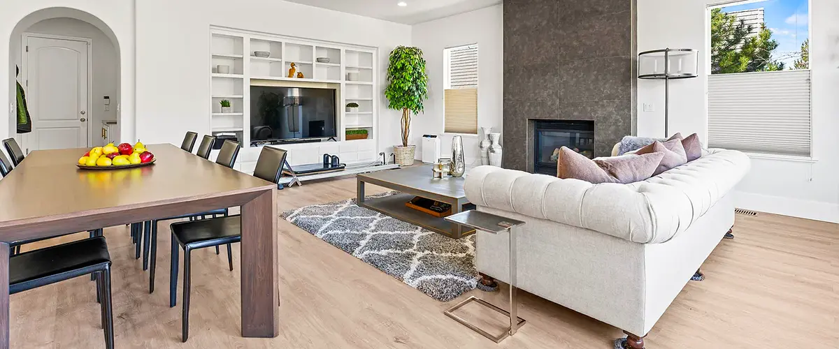 Spacious living room with built-in shelving, modern fireplace, and dining area, featuring neutral tones and minimalist decor.