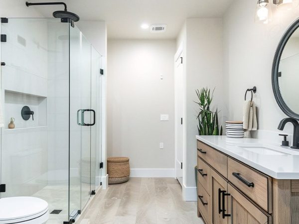 Contemporary bathroom with glass-enclosed, frameless shower doors, wood vanity, and black fixtures - modern bathroom design and renovation.